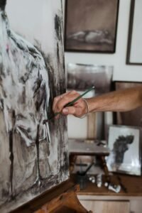 Close-up of an artist painting on canvas with a brush in an art studio.